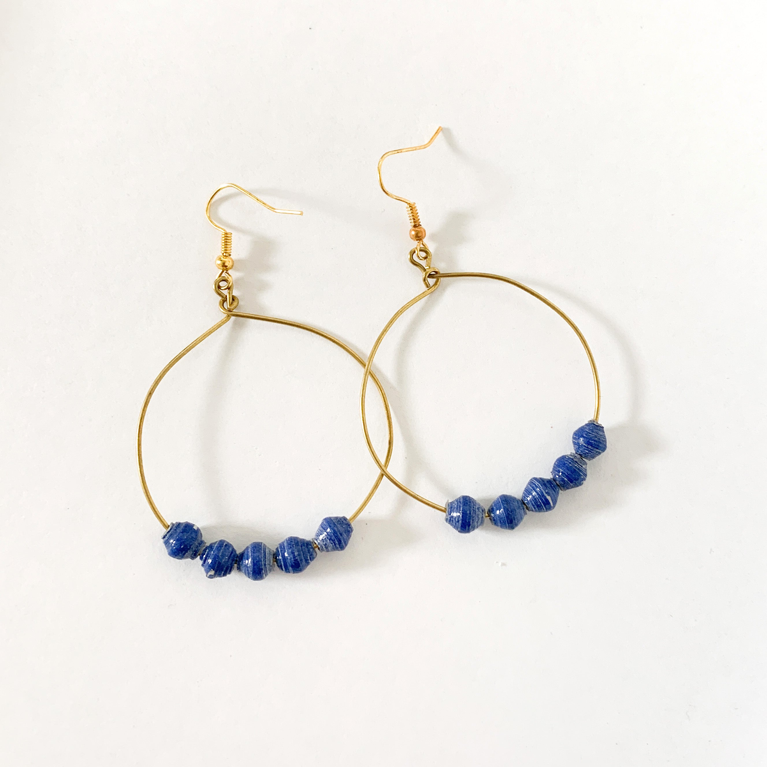 JustOne's brass hoop earrings with five blue paper beads on the bottom of the hoop, handcrafted in Uganda