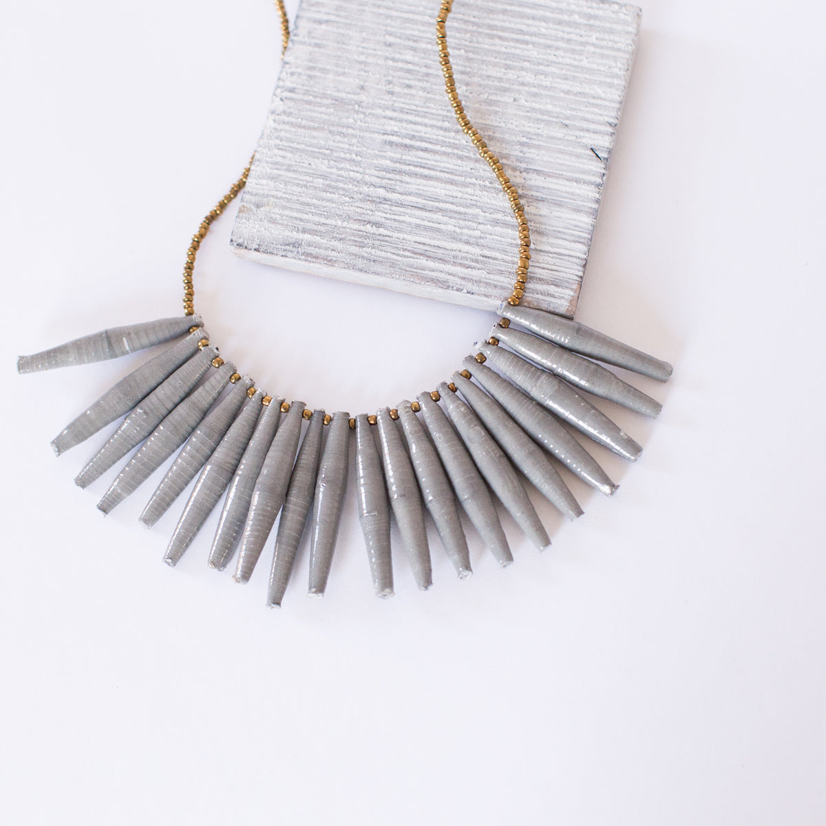 JustOne's necklace with long grey paper beads dangling off, handcrafted in Uganda